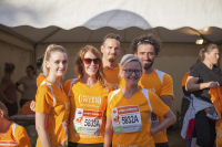 Foto einer Gruppe von drei Frauen und zwei Männern welche orangene T-Shirts vom Fonds Soziales Wien tragen und in die Kamera blicken.